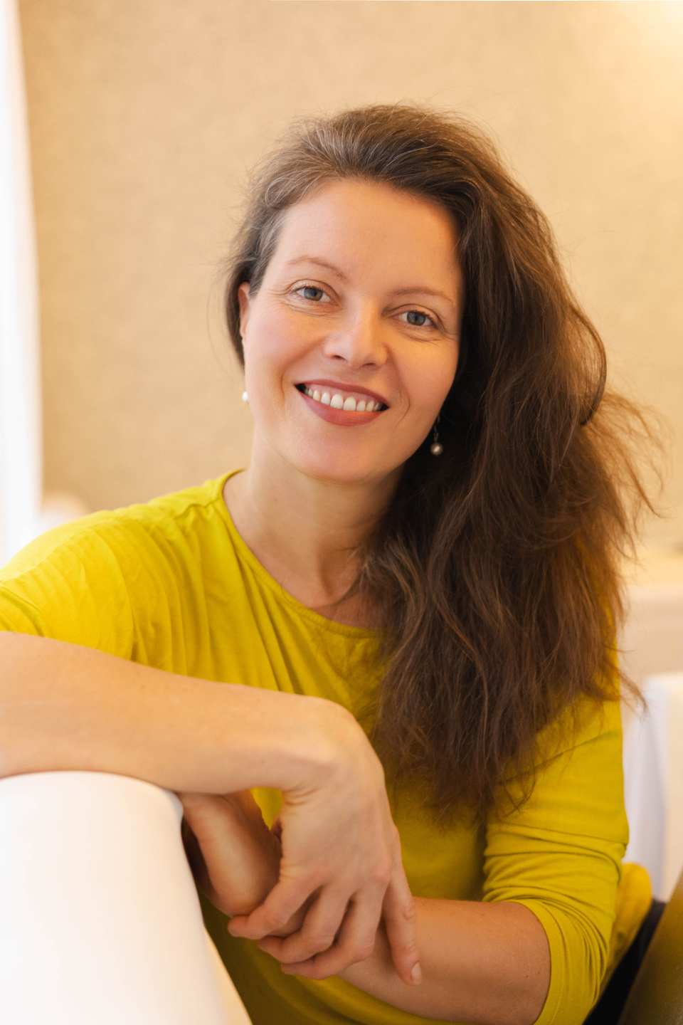 Kateřina Halamová sedí opřená o opěradlo židle a usmívá se